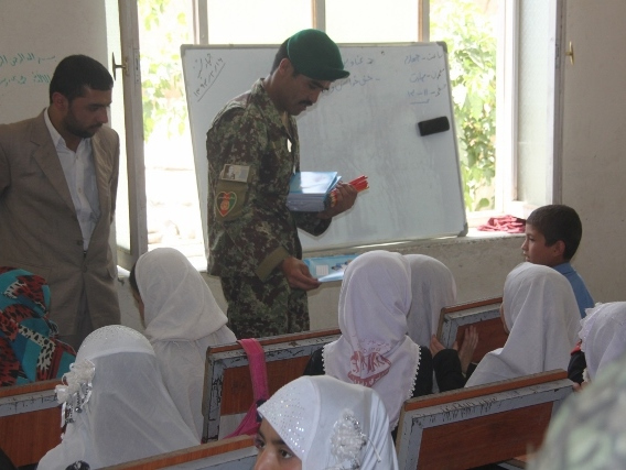 Příslušník afghánské armády při předávání školních pomůcek ve smíšené škole v provincii Parwan.