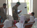 Příslušník afghánské armády při předávání školních pomůcek ve smíšené škole v provincii Parwan.