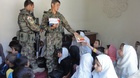  Příslušníci Afghánské národní armády předávají dětem sešity