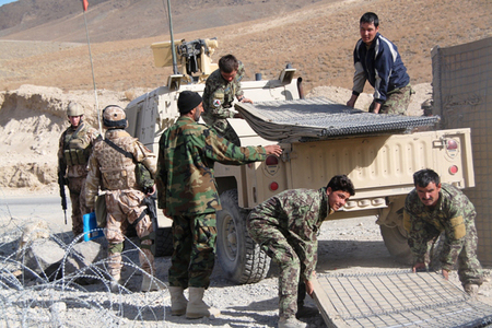 Afghánští vojáci skládají nové Hesco valy, které jim přivezli čeští vojáci.