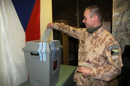 Voják českého provinčního rekonstrukčního týmu vhazuje obálku s hlasovacím lístkem do urny.