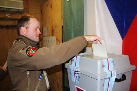 Voják českého provinčního rekonstrukčního týmu vhazuje obálku s hlasovacím lístkem do urny.