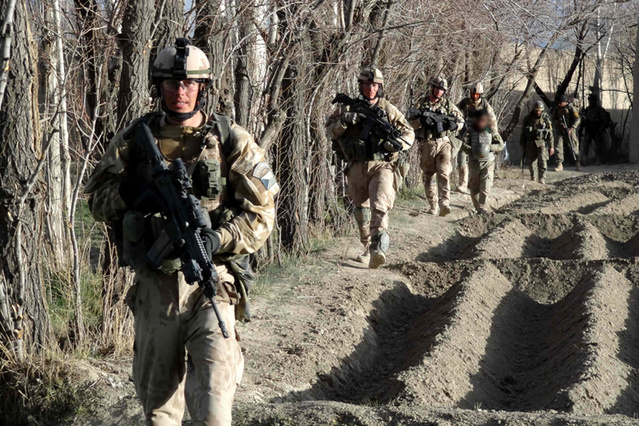 Češi postupují při okraji pole během operace Welcome Home, v pozadí za nimi příslušníci Afghánské národní armády
