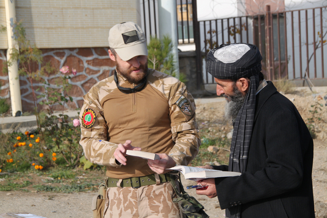 Por. Daniel S. z týmu PSYOPS při předávání učebnic řediteli školy v distriktu Khoshi