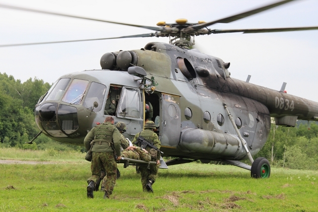 Vojáci nakládají raněného kolegu do vrtulníku. 