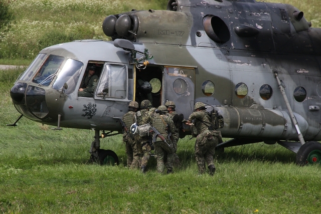 Slovenští vojáci nakládají zraněného kolegu do vrtulníku. 