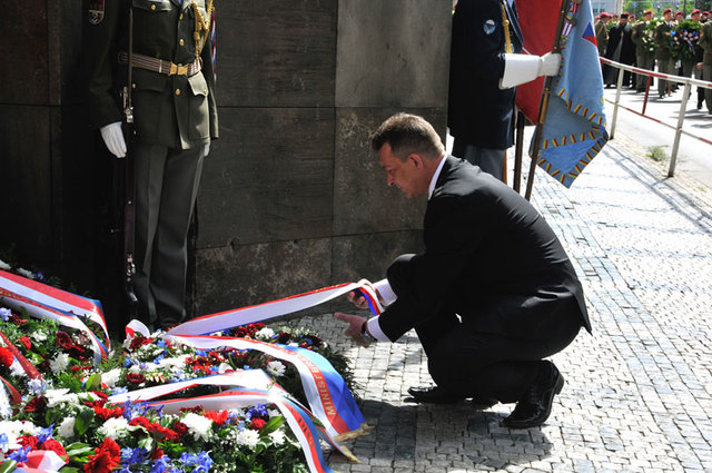 Státní tajemník Ministerstva obrany ČR Petr Vančura upravuje stuhy na smutečním věnci 