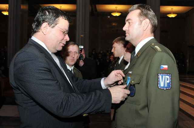Ministr Alexandr Vondra předává jednomu z vojenských policistů ocenění za dosavadní práci