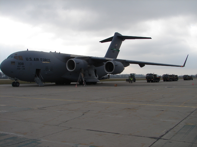 Příjezd vozidel k letounu na letištní stojánce