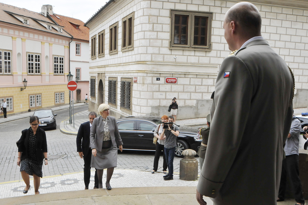 Ministryně obrany přijíždí k vojenskému kostelu na ekumenickou bohoslužbu. Před vchodem ji vítá hlavní kaplan