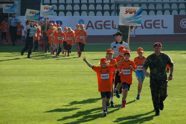 Malí soutěžící v doprovodu vojáků přibíhají na stadion