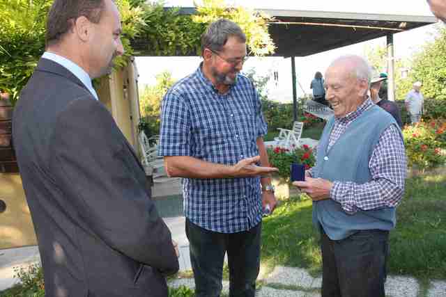  Milan Bachan předává jednomu z majitelů pozemku, na němž je umístěna pamětní deska popravy našich legionářů medaili Piava – Doss Alto