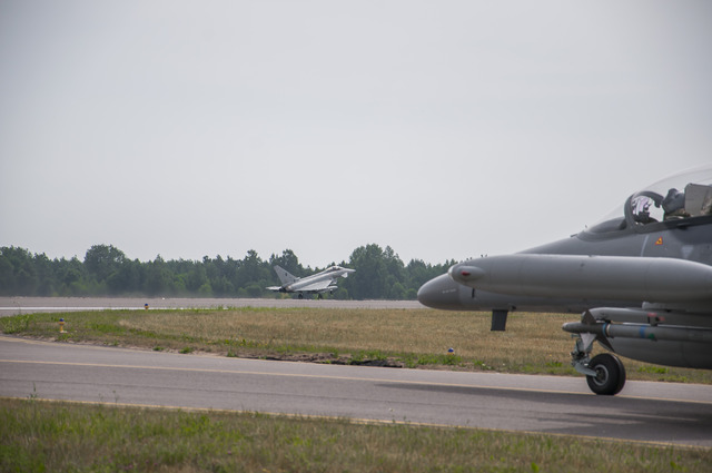 Italský Eurofighter Typhon při vzletu (vlevo) a český L-159 pojíždí na vzletovou a přistávací dráhu litevské základny Šiauliai