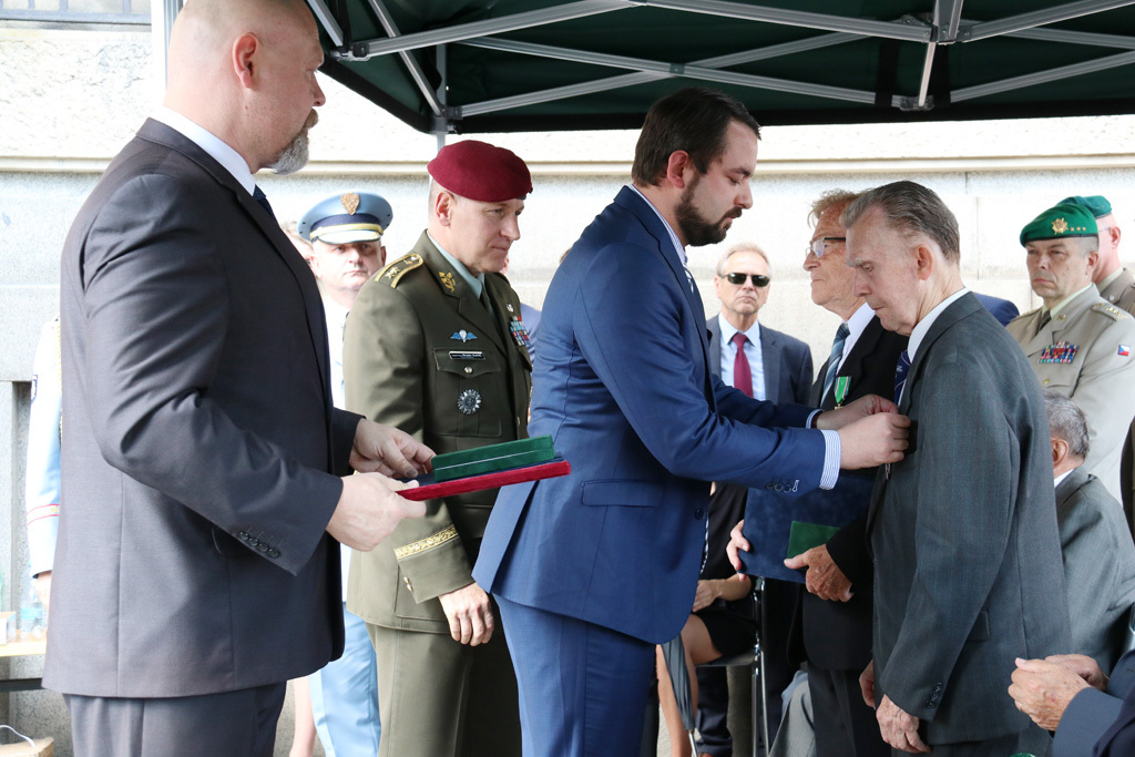 Pověřený náměstek ministra obrany Filip Říha předává Záslužný kříž ministra obrany III. stupně  Janu a Karlu Píkovým, synovcům generála Heliodora Píky. Gratuluje jim i zástupce náčelníka Generálního štábu – náčelník štábu generálmajor Miroslav Hlaváč