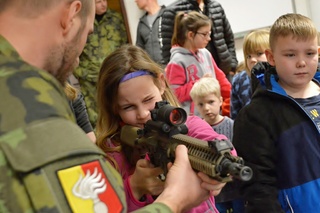 Dívka si prohlíží jednu ze zbraní vojenských policistů