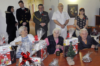 Veteráni a členové jejich rodin s vánočními dárkovými balíčky. 