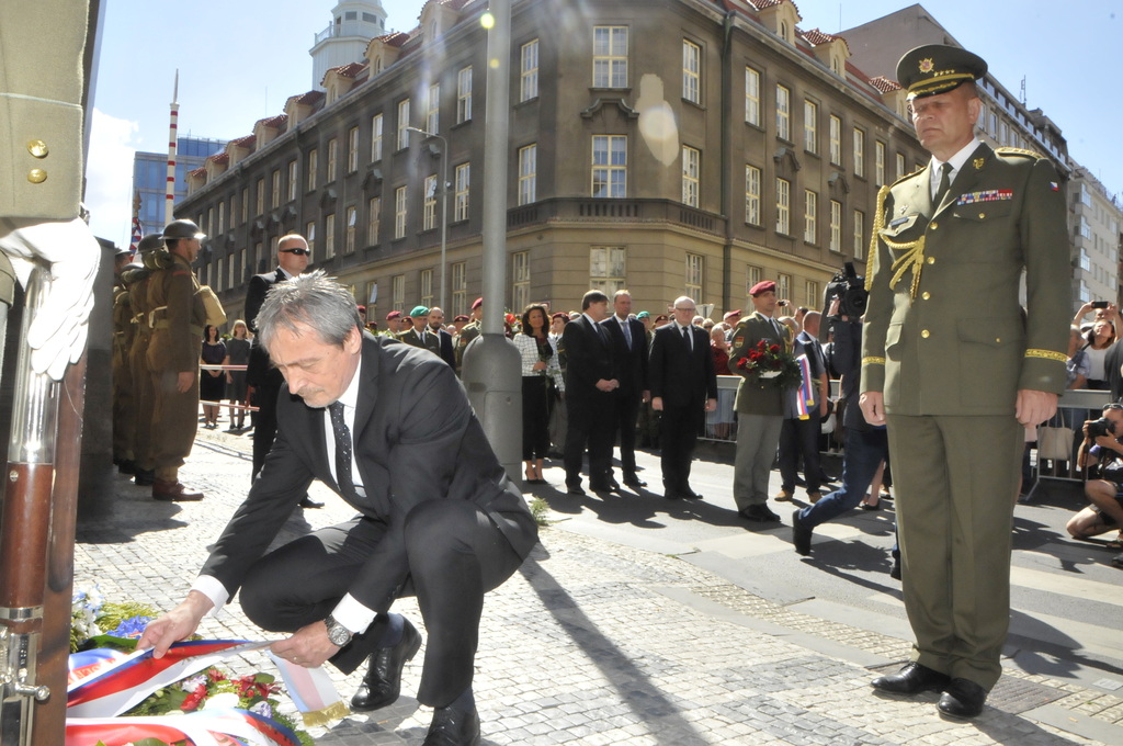 Martin Stropnický symbolicky urovnává stuhy na věnci u pamětní desky parašutistů.