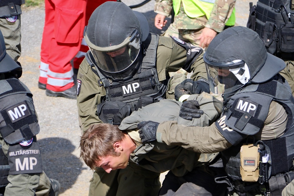 Komando Vojenské policie odvádí spoutaného migranta