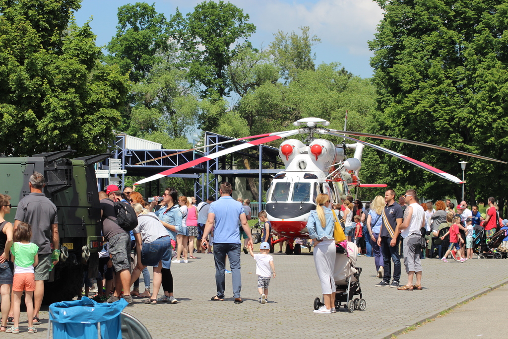 Diváci stojí ve dvou dlouhých frontách z jedné i druhé strany vrtulníku Sokol W-3A