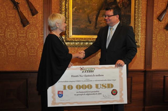 Prezidentka hnutí Na vlastních nohou Běla Gran Jensen předává šek na 10 tisíc USD ministru obrany Alexandru Vondrovi