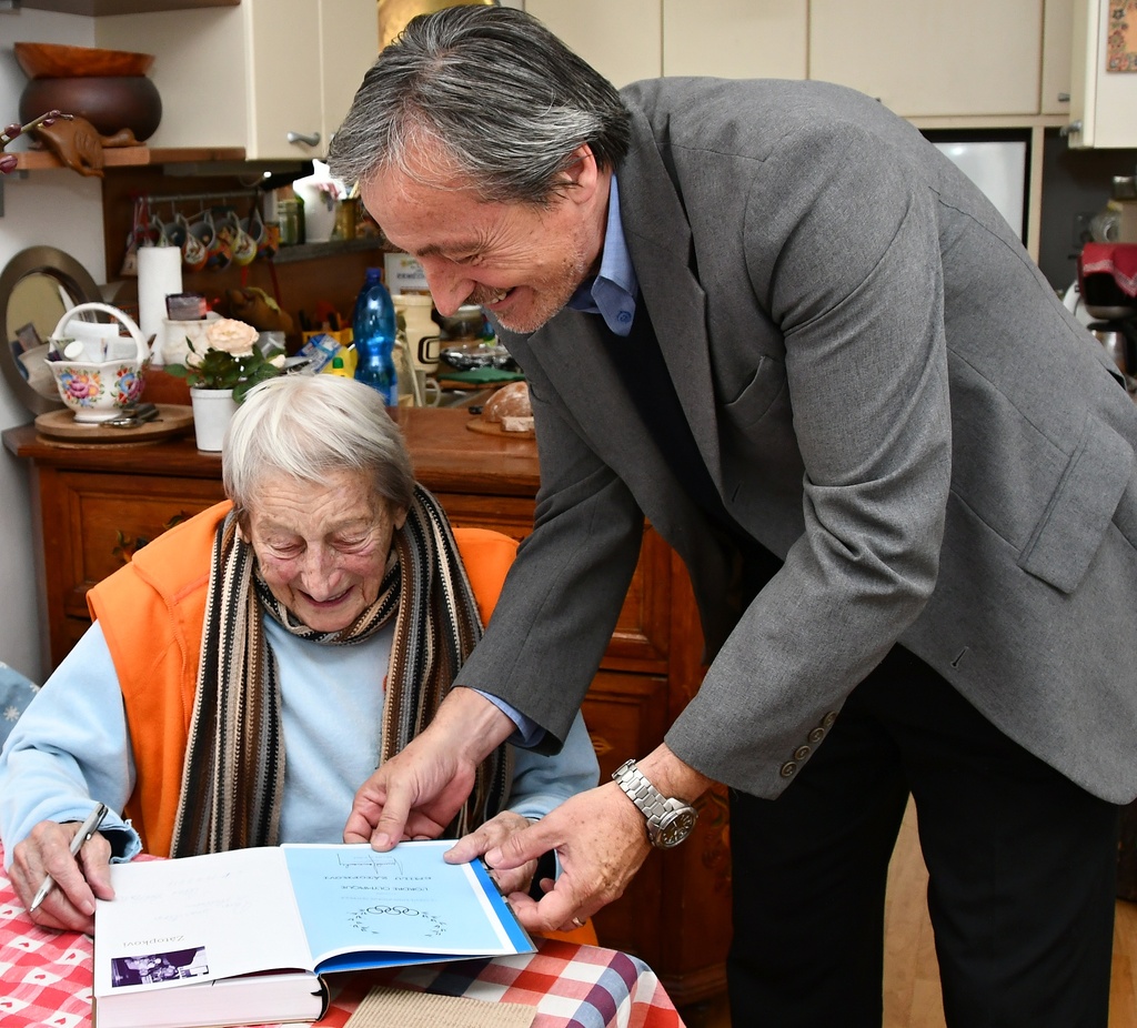 Dana Zátopková ministru obrany podepisuje autorskou knihu Náš život pod pěti kruhy