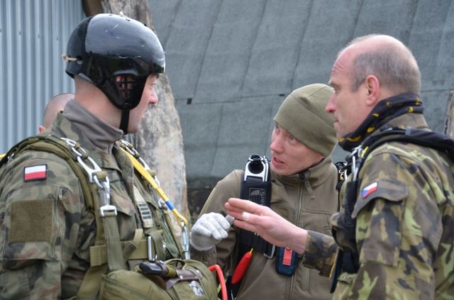 Poručík Tomáš Starý a praporčík Miroslav Kmošek vysvětlují polskému instruktorovi, jak nejlépe přistát na českém padáku OVP 12 SL