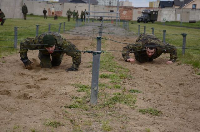 Soutěžící při zdolávání překážky drátěné sítě