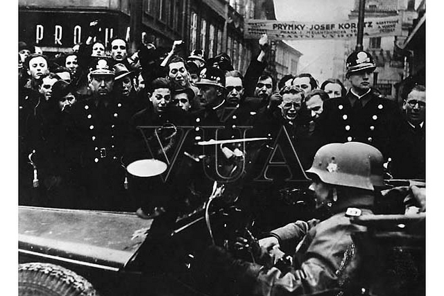Výmluvné obrázky pražských ulic z 15. března 1939. Zatímco Češi hrozí pěstmi, většina pražských Němců vítá německou armádu zdviženou pravicí. (Zdroj VÚA)